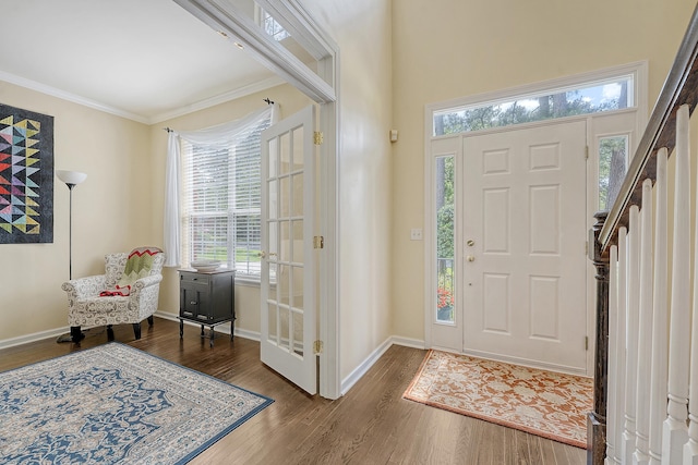 foyer entrance featuring wood finished floors, ornamental molding, and baseboards