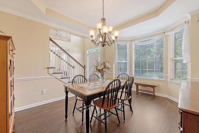 dining space with dark wood-type flooring, a raised ceiling, a chandelier, baseboards, and stairs