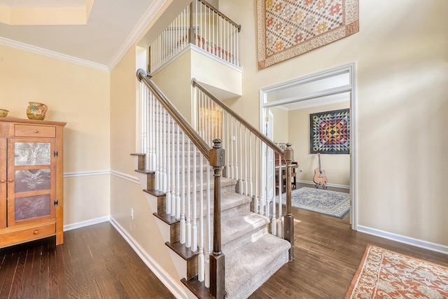 staircase with wood finished floors, baseboards, and crown molding
