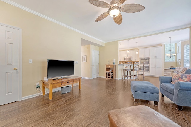 living area featuring crown molding, a ceiling fan, baseboards, and wood finished floors
