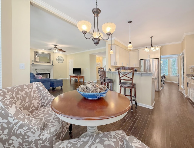dining area featuring ceiling fan, a chandelier, dark wood-style floors, a premium fireplace, and baseboards