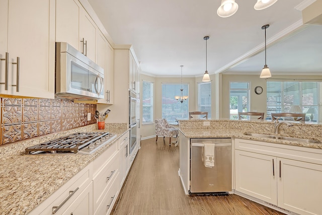kitchen with appliances with stainless steel finishes, a sink, ornamental molding, light wood finished floors, and backsplash