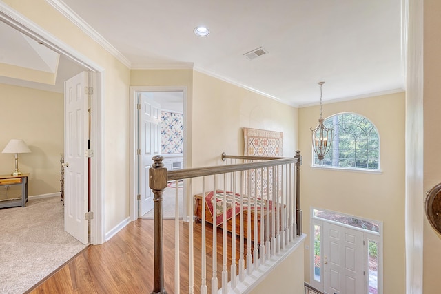 hallway featuring an upstairs landing, a chandelier, light wood-type flooring, baseboards, and ornamental molding