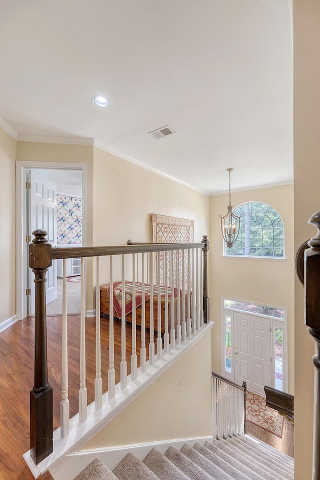 staircase featuring wood finished floors, a chandelier, crown molding, baseboards, and recessed lighting