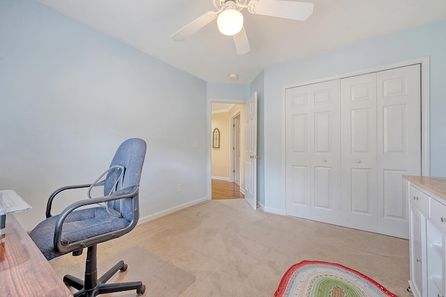 unfurnished office with light colored carpet, ceiling fan, and baseboards