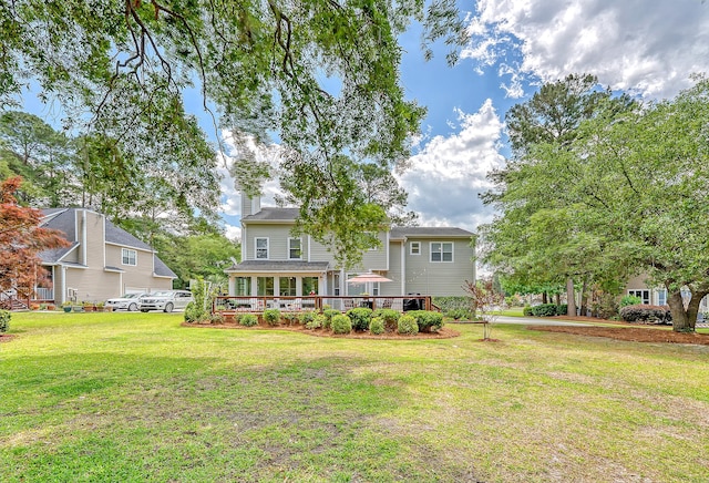 rear view of house featuring a yard, a deck, and a chimney