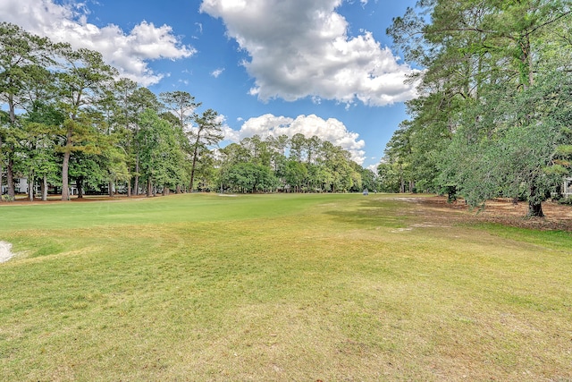 view of green lawn featuring view of scattered trees and golf course view