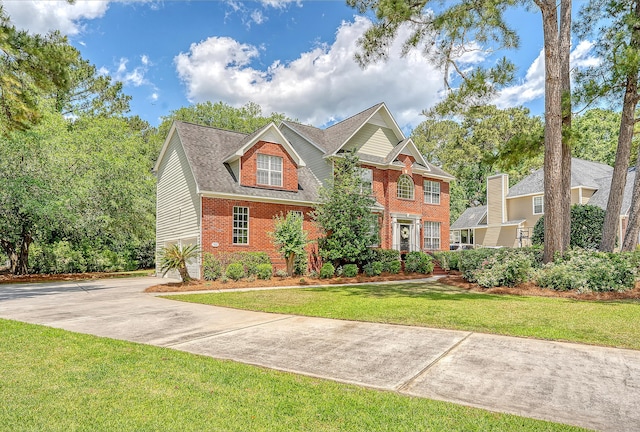 view of front of home featuring brick siding, concrete driveway, and a front lawn