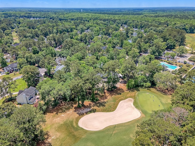 aerial view of property's location with a golf course and a heavily wooded area