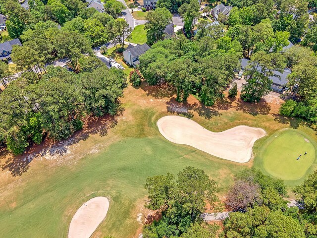 view of property location with a tree filled landscape, a golf club, and nearby suburban area
