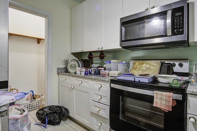 kitchen featuring white cabinetry, light tile patterned flooring, and light stone counters