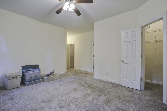 unfurnished bedroom with ceiling fan, a closet, a spacious closet, and carpet