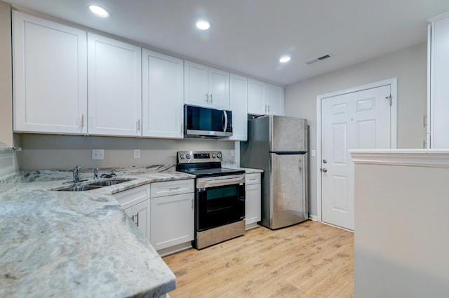 kitchen featuring light wood-type flooring, white cabinetry, stainless steel appliances, and a sink