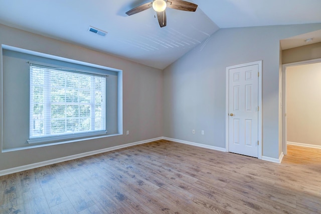 spare room with vaulted ceiling, wood finished floors, visible vents, and a ceiling fan