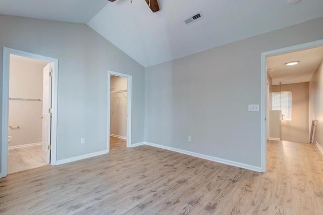 unfurnished bedroom with vaulted ceiling, light wood finished floors, a walk in closet, and visible vents