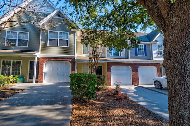 townhome / multi-family property with a garage, brick siding, and driveway