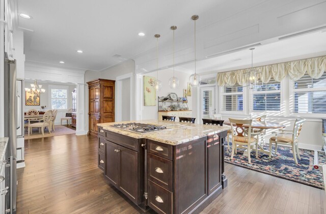 828 Bridge Point Cir, Mount Pleasant, SC 29464 - kitchen featuring dark wood-style flooring, stainless steel gas cooktop, crown molding, a chandelier, and light stone counters