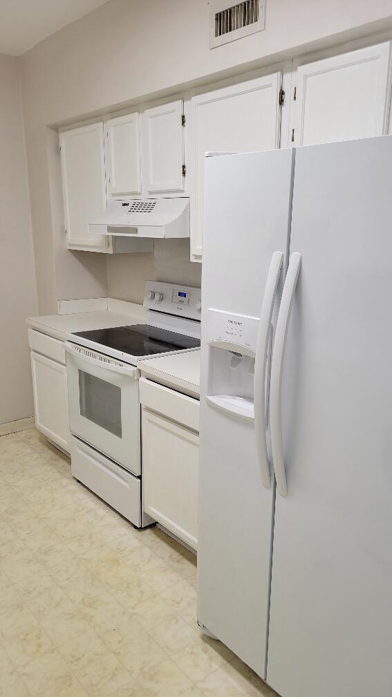 kitchen featuring white appliances, white cabinetry, visible vents, and under cabinet range hood