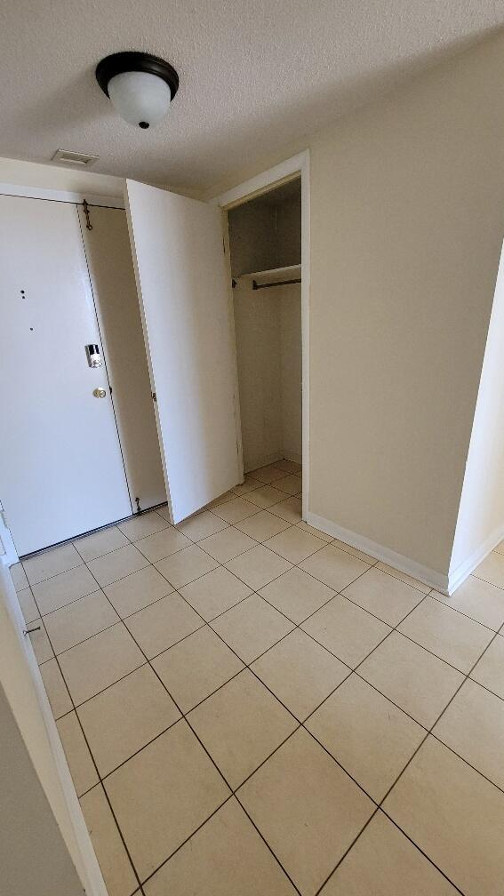 unfurnished bedroom featuring light tile patterned floors, a closet, visible vents, and a textured ceiling