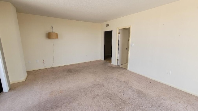 carpeted spare room featuring visible vents and a textured ceiling