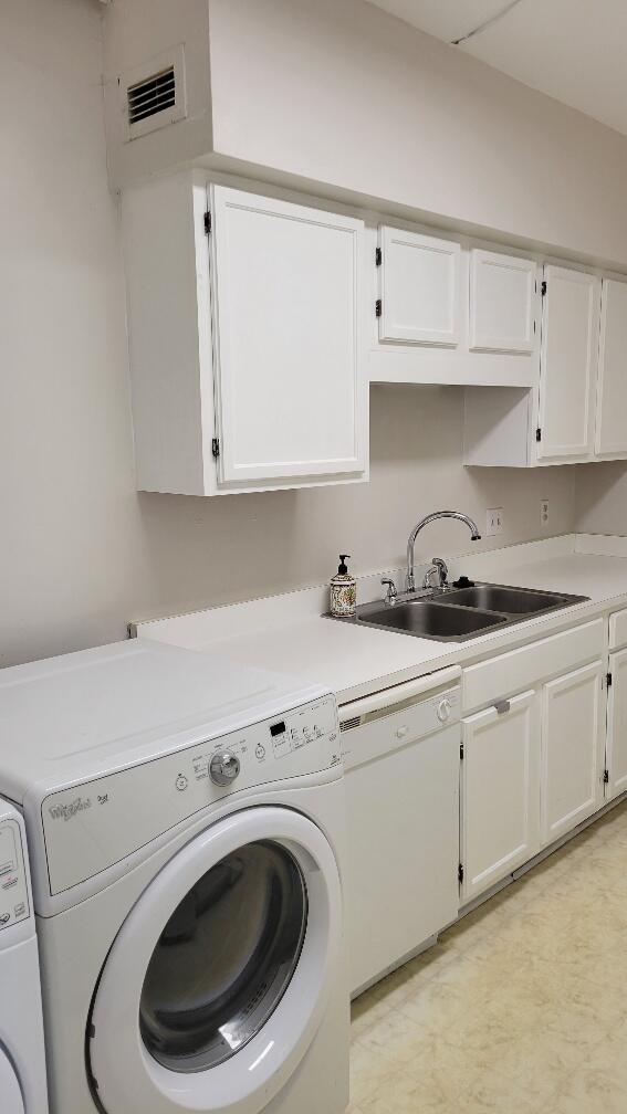 laundry area featuring cabinet space, visible vents, independent washer and dryer, light floors, and a sink