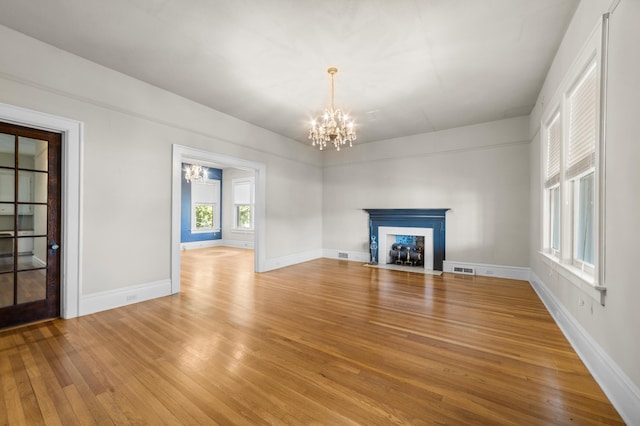 unfurnished living room with hardwood / wood-style floors and an inviting chandelier