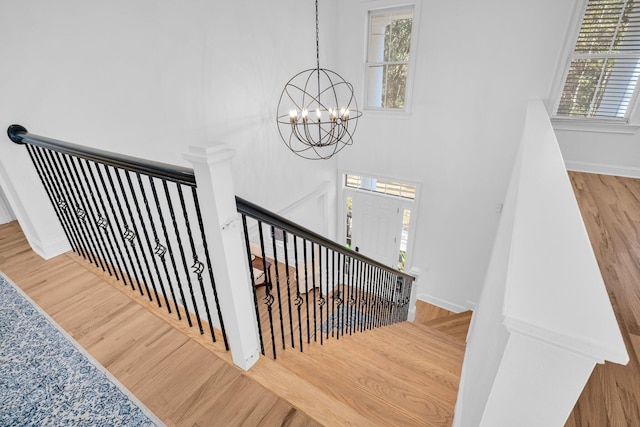 staircase with hardwood / wood-style floors and a notable chandelier