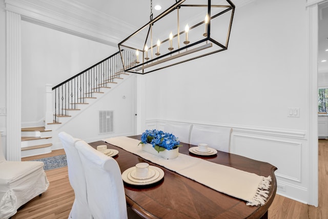 dining area featuring hardwood / wood-style flooring, crown molding, and a notable chandelier