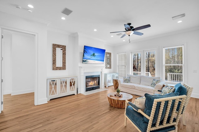 living room featuring ceiling fan, light wood-type flooring, and crown molding