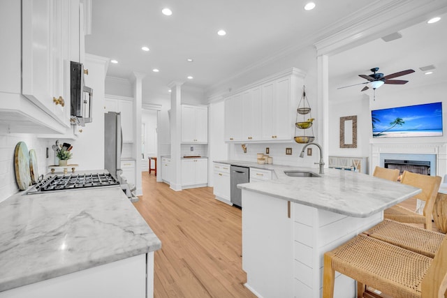 kitchen featuring backsplash, kitchen peninsula, sink, white cabinetry, and a kitchen breakfast bar