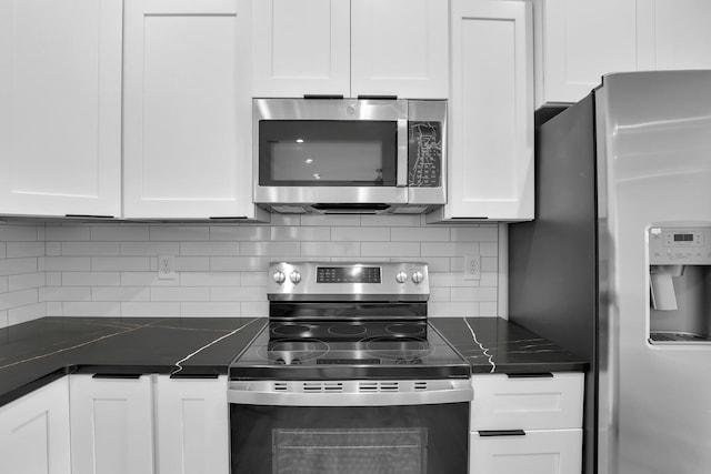 kitchen with stainless steel appliances, dark countertops, white cabinets, and backsplash