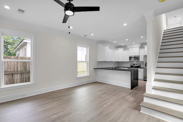 kitchen with appliances with stainless steel finishes, plenty of natural light, dark countertops, a peninsula, and recessed lighting