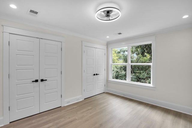 unfurnished bedroom with multiple closets, baseboards, light wood-type flooring, and recessed lighting