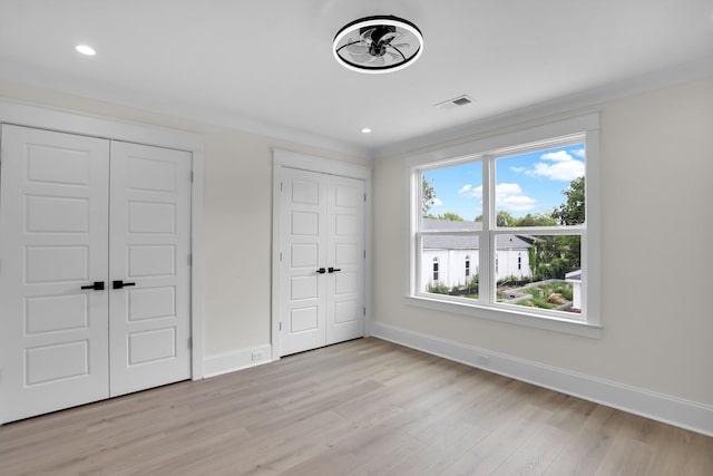 unfurnished bedroom featuring multiple closets, baseboards, light wood-style flooring, and recessed lighting