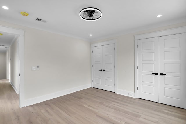 unfurnished bedroom with light wood finished floors, baseboards, recessed lighting, and two closets