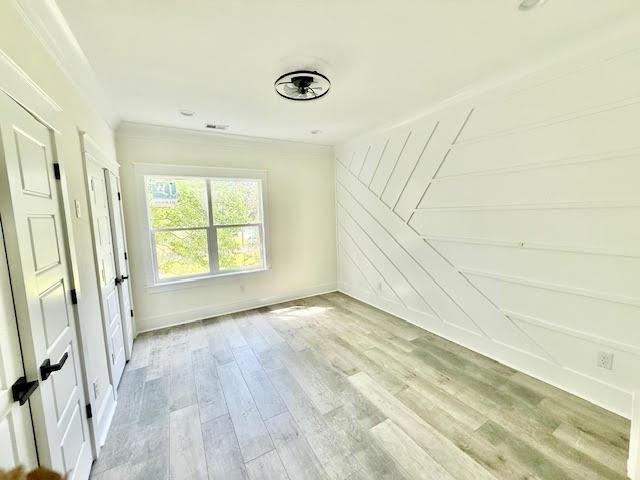 unfurnished room featuring light wood-style floors, baseboards, and ornamental molding