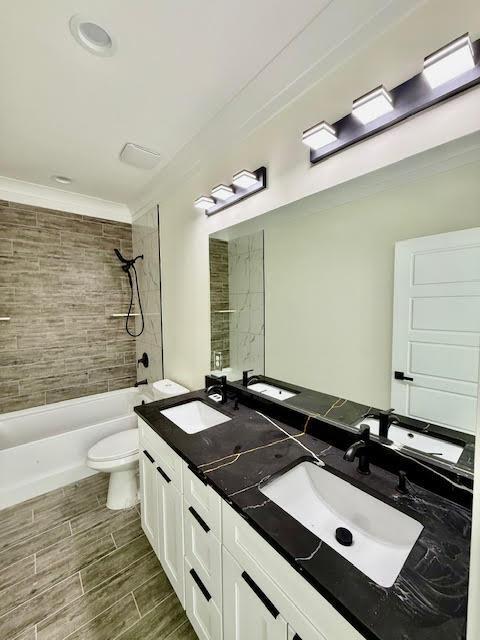 full bathroom featuring toilet,  shower combination, double vanity, crown molding, and wood finished floors