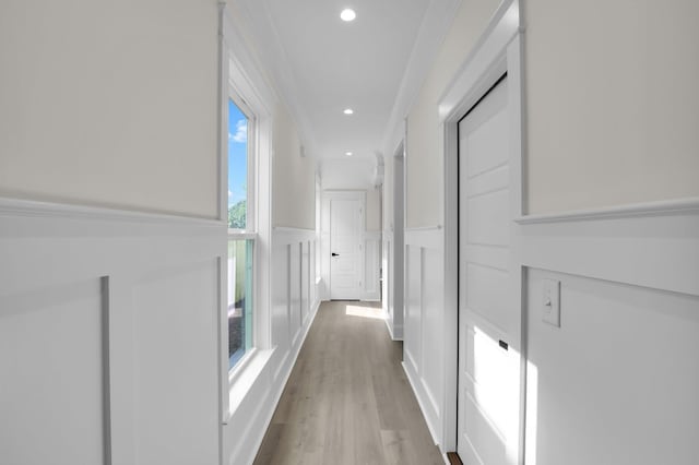 hallway featuring light wood-style floors, recessed lighting, a decorative wall, and wainscoting