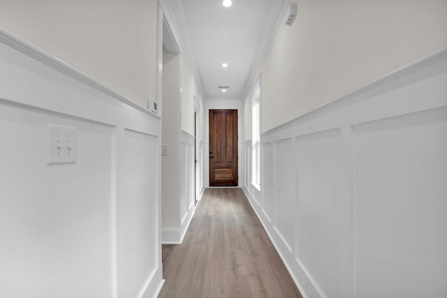 hallway featuring a decorative wall, wood finished floors, recessed lighting, and wainscoting