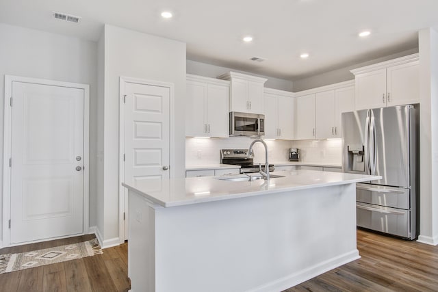 kitchen featuring stainless steel appliances, visible vents, a sink, and dark wood-style floors