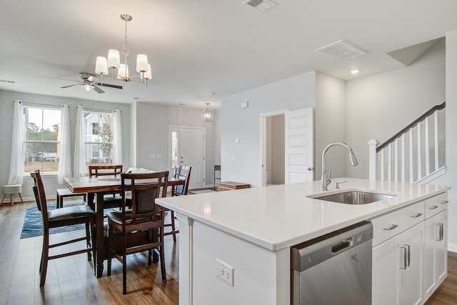 kitchen featuring visible vents, hanging light fixtures, stainless steel dishwasher, white cabinetry, and a sink