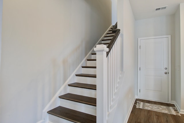 stairs with wood finished floors, visible vents, and baseboards