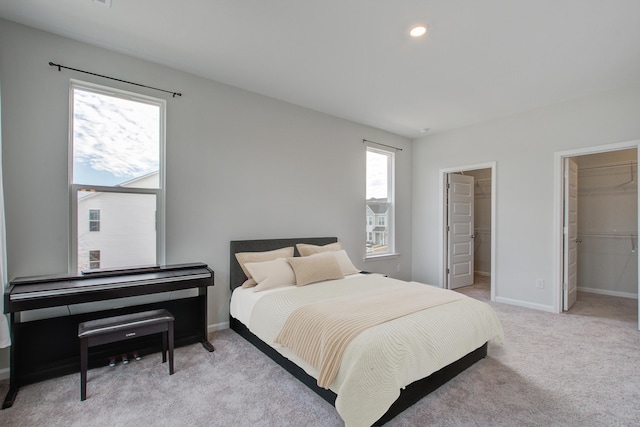 bedroom with light carpet, a spacious closet, baseboards, and recessed lighting