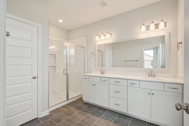 full bath featuring double vanity, a stall shower, visible vents, and a sink