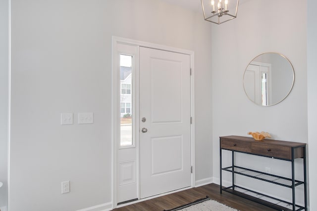 foyer entrance featuring dark wood-type flooring, an inviting chandelier, and baseboards