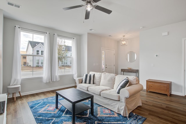 living area with baseboards, visible vents, wood finished floors, and ceiling fan with notable chandelier