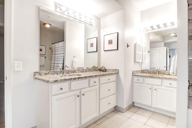 bathroom featuring a sink, baseboards, tile patterned flooring, and two vanities