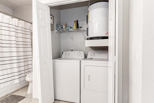 laundry area with light tile patterned floors, water heater, laundry area, and independent washer and dryer