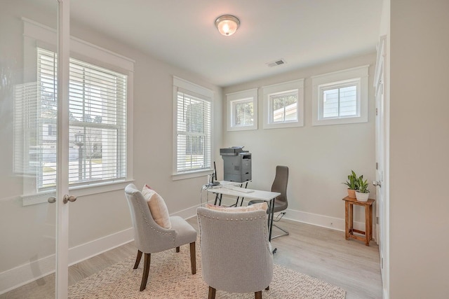 home office with light wood-type flooring and a healthy amount of sunlight