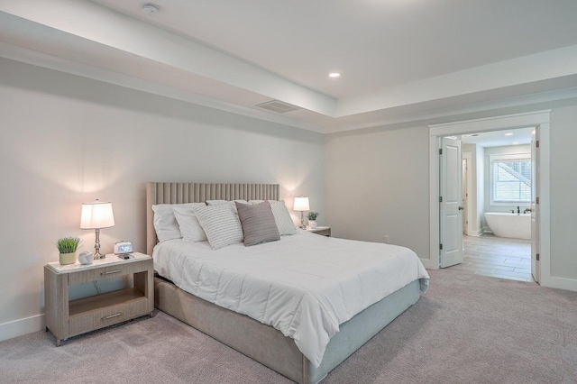 bedroom featuring connected bathroom and light carpet